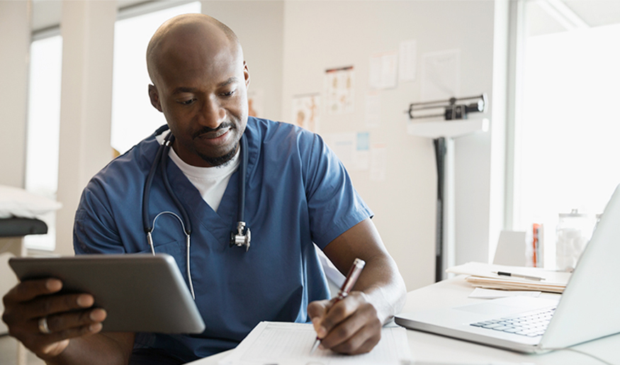 Health care worker making notes and holding a tablet