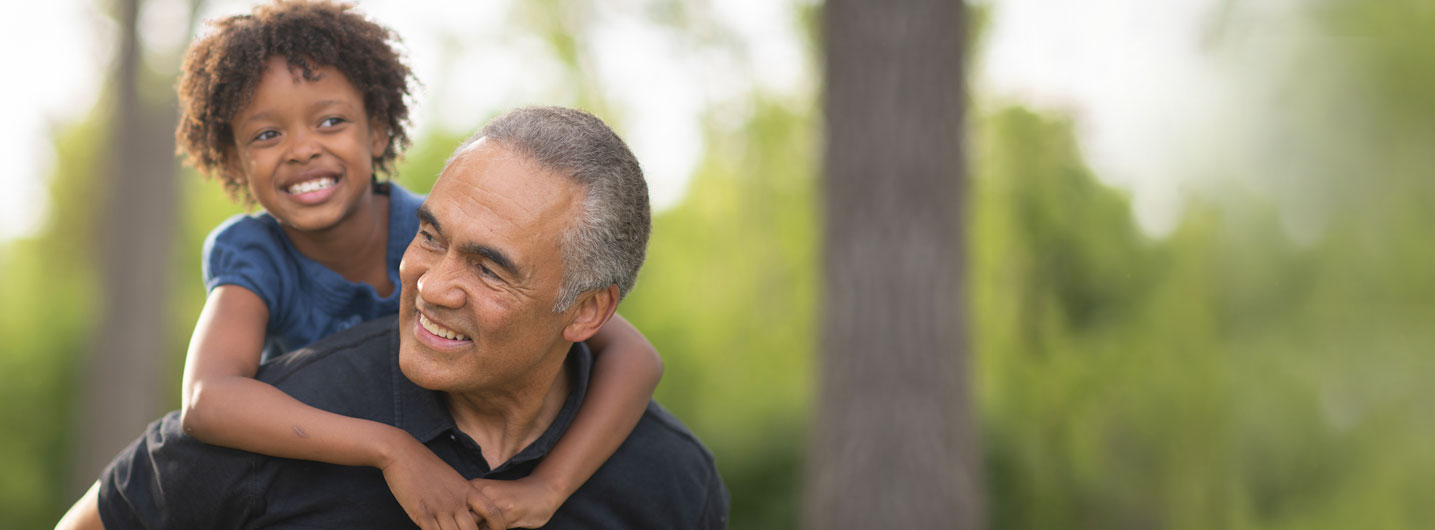 Grandfather carrying grandchild on shoulders in park