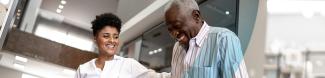 A health care worker with their hand on the arm of an elderly patient in a clinic.